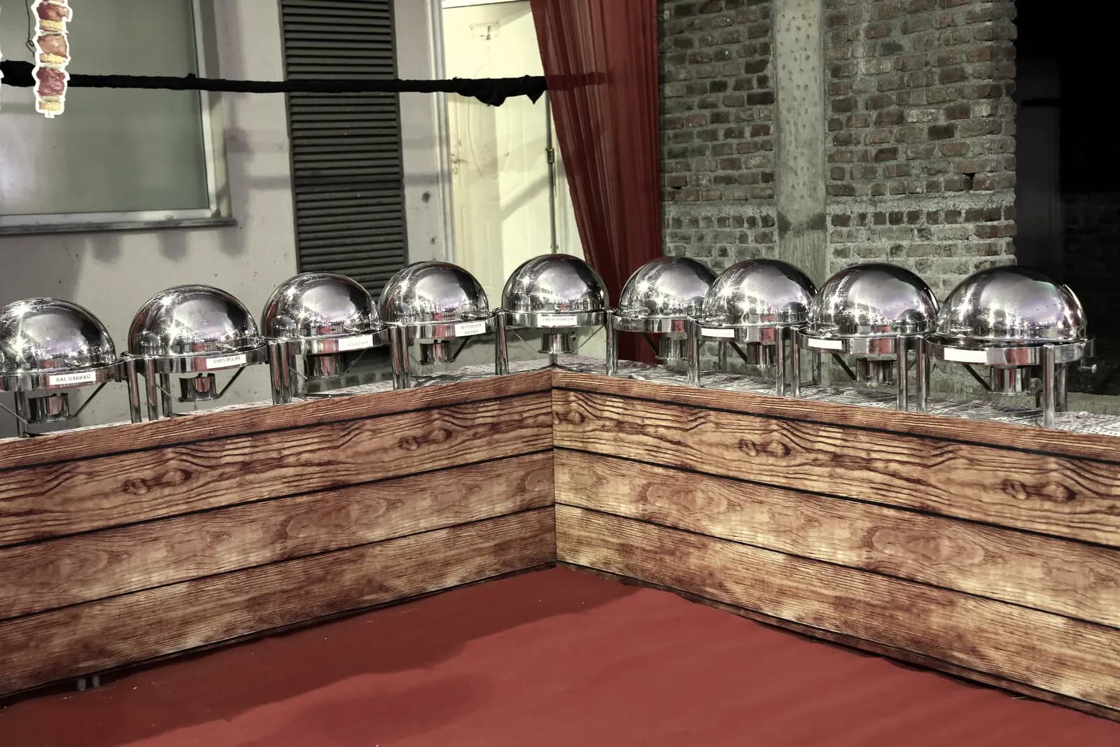A timber-fronted service counter with a row of polished chafing domes ready for service.