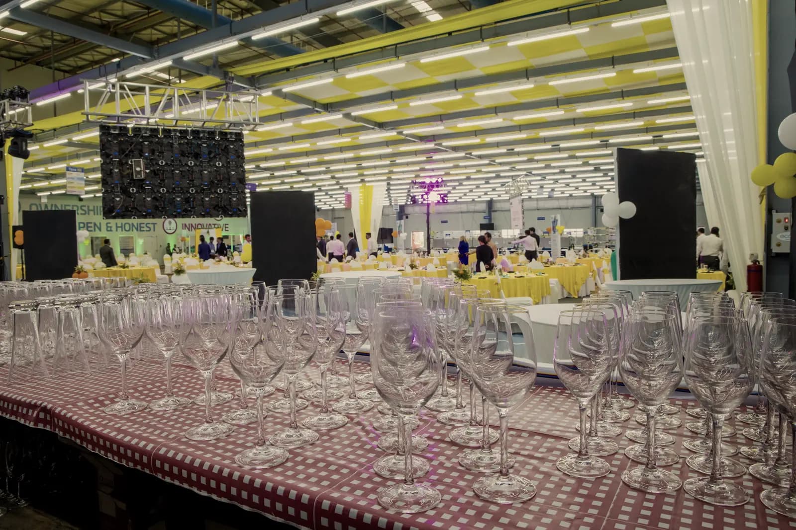 Wine glasses set out in close ranks along a dressed table, catching the room light.