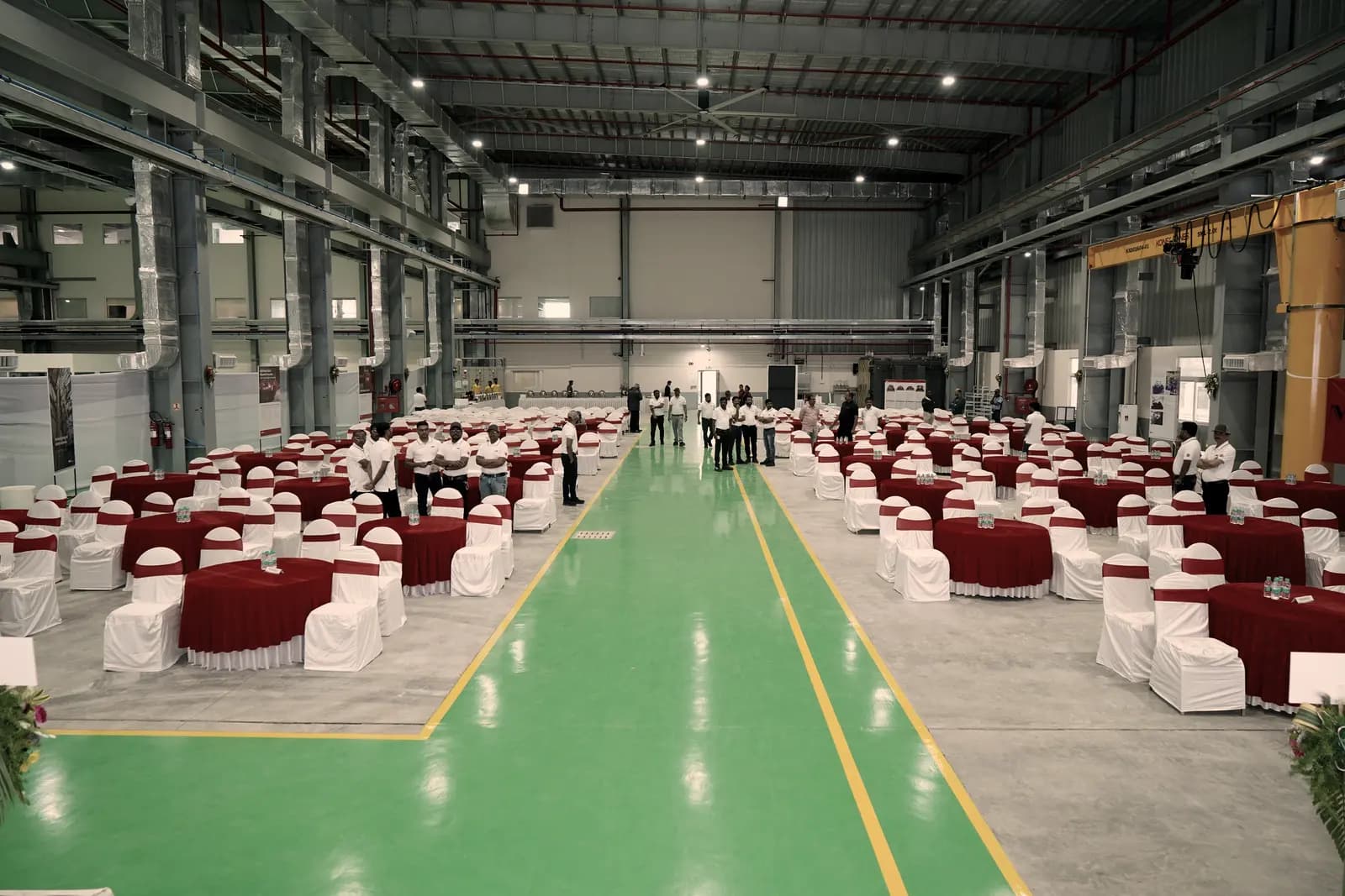 A working plant floor turned over to seating, a green walkway running down the centre of the hall.