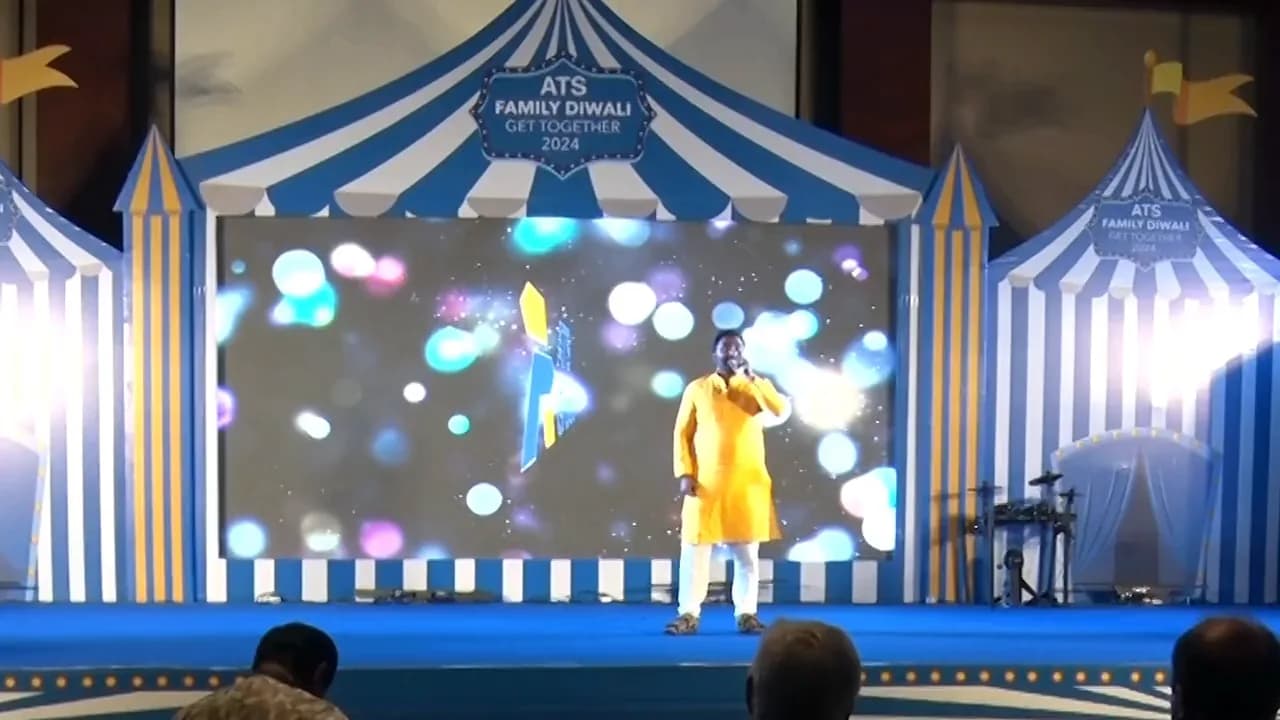 A draped stage arch in deep blue and violet, costumed performers, and a seated audience filling the room.